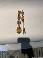 Carved wooden spoon and fork servers side by side on white background