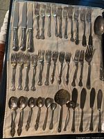 All 38 pieces of assorted flatware laid out on cloth