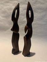 Front view of two abstract carved wood figurines showing overall design and condition