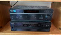 Front view of Sony STR-DE197 receiver stacked above Onkyo DX-C390 CD changer inside wooden shelf