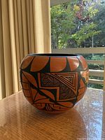 Front view of rounded Jemez Pueblo vase showing geometric black designs on orange clay
