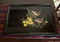 Full view of rectangular black Couroc tray with bird and flower inlay