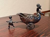 Side view showing entire cart, cherub pulling, bowl detail, wheels