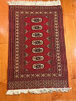 Full view of rectangular red wool rug with fringe