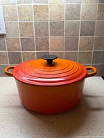 Dutch oven with lid showing flame orange exterior and black knob