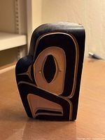 Front-angled view of the carved wooden bird figure showing formline design and color contrast