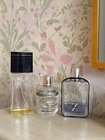 Front view of three perfume bottles displaying shapes, caps, branding and fill levels