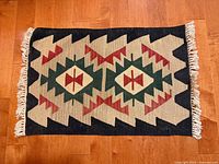 Full view of rug laid horizontally showing full pattern and left fringe