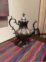 Full view of ornate silverplate teapot on pedestal base