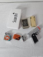 Group shot of seven assorted lighters plus Scorch Torch box