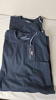 Two stacked blue Vineyard Vines pocket T-shirts with tags visible
