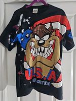 Front view of black T-shirt with Taz graphic and USA flag background
