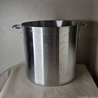 Front view of large stock pot showing brushed metal exterior and handle