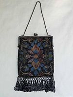 Full view of beaded purse hanging, showing chain, frame and fringe