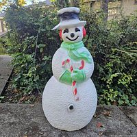 Front view of snowman blow mold showing hat, earmuffs, scarf, candy cane and lighting cavity