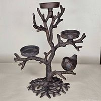 Front view of cast iron tree candle holder with three cups and bird figure