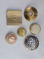 All six compacts and pill box arranged for overview
