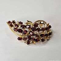 Front view of gold vermeil brooch with garnet and glass stones