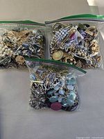 Three plastic bags filled with assorted vintage jewelry pieces