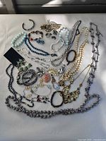 Full lot overview showing necklaces, bracelets, brooches and earrings spread on surface