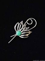 Front view of sterling flower brooch with green cabochon