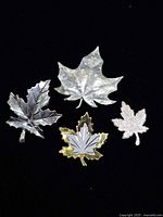 front view of four sterling maple leaf brooches