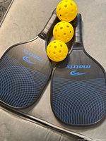 Two Matrix paddles and three yellow balls