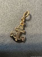 Front view of gold-tone anchor pendant showing cross detail and bail