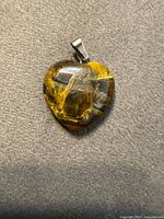 Front view of heart-shaped tiger’s eye pendant showing golden chatoyancy