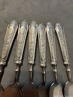 Close view of all six spoons showing ornate handles and spoon bowls