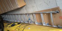 Full view of aluminum extension ladder resting on kayak and against wall