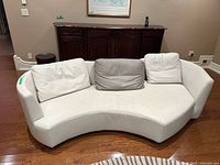 Full view curved Roche Bobois leather sofa with three cushions