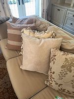 Three of the pillows on couch: plaid, damask, leaf tapestry plus glimpse of others