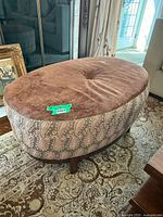 Oval ottoman front angle showing top fabric, side pattern, and legs