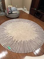 Full view of round Roche Bobois rug on hardwood floor