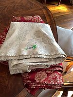 Folded ivory and red damask linens stacked on table