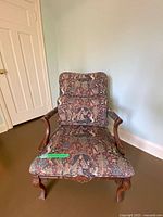Front view of carved wood armchair with tapestry upholstery