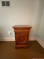 Front view of wooden nightstand showing drawer and cupboard door