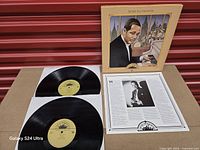 Open box showing two vinyl discs, inner sheet and cover