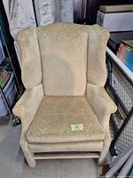 Front view of beige wingback armchair showing overall design and fabric pattern