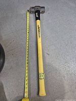 Full view of sledgehammer beside tape showing ~34 in length