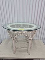 Angled view showing entire table with glass top and wicker base