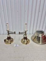 Pair of brass articulating lamp bases and one detached metal shade on table