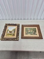 Both framed paintings side by side on table