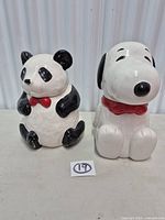 Front view of both panda and Snoopy cookie jars with lids