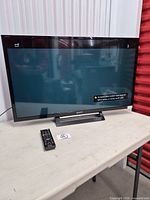 Front view of Sony 32" TV on stand with remote