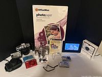 Group shot of all seven cameras, accessories, and OfficeMax photo paper