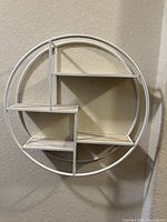 Empty white metal circular wall shelf, showing five tiers