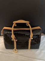 Front and top view of black patent Arcadia handbag showing tan handles, trim and gold hardware