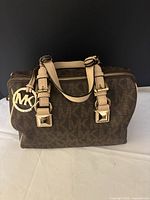 Front view of Michael Kors Grayson handbag showing MK monogram, leather handles, gold hardware and hang tag